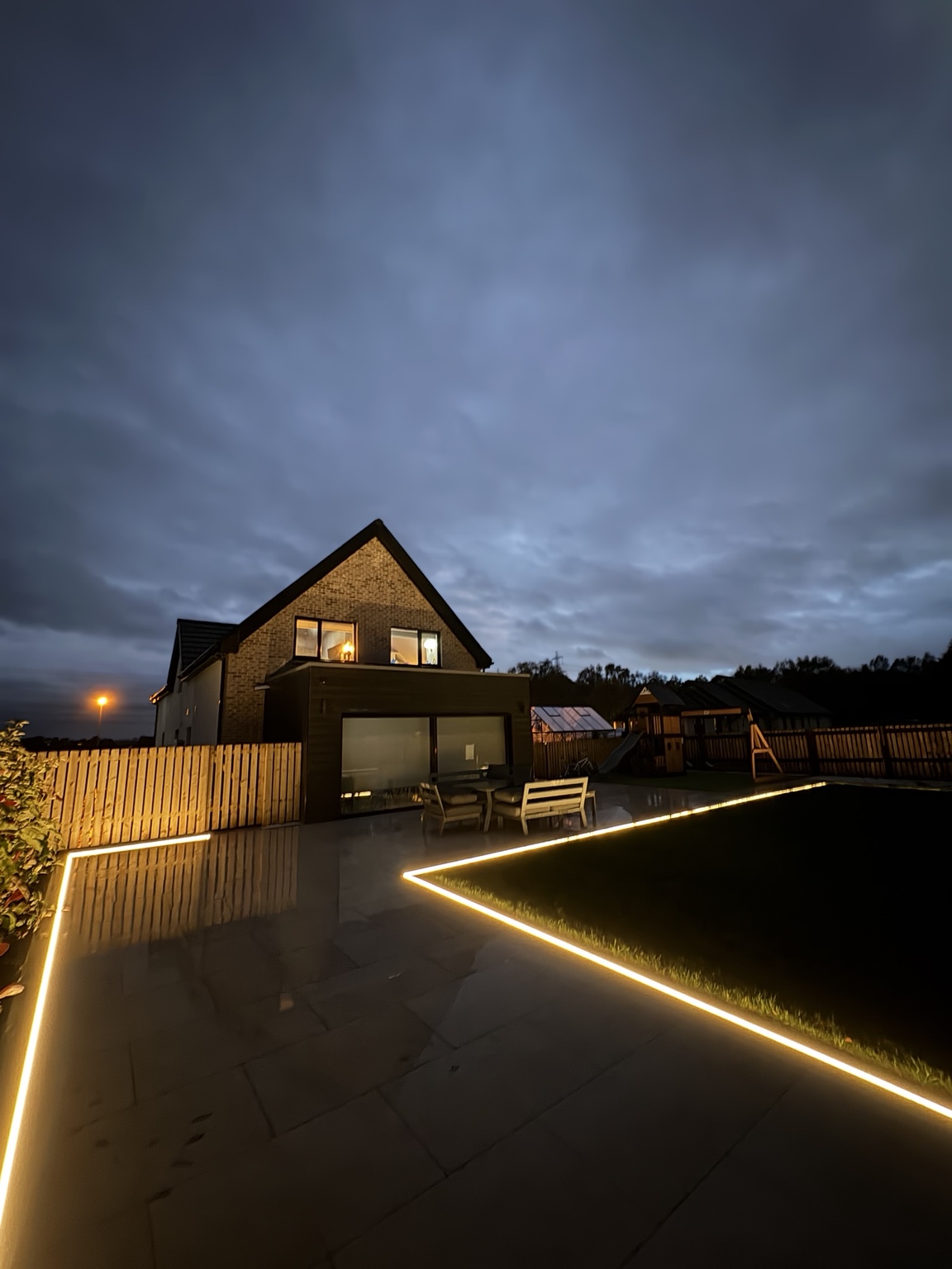 Paved terrace and lawn in Airth with illuminated edges at dusk