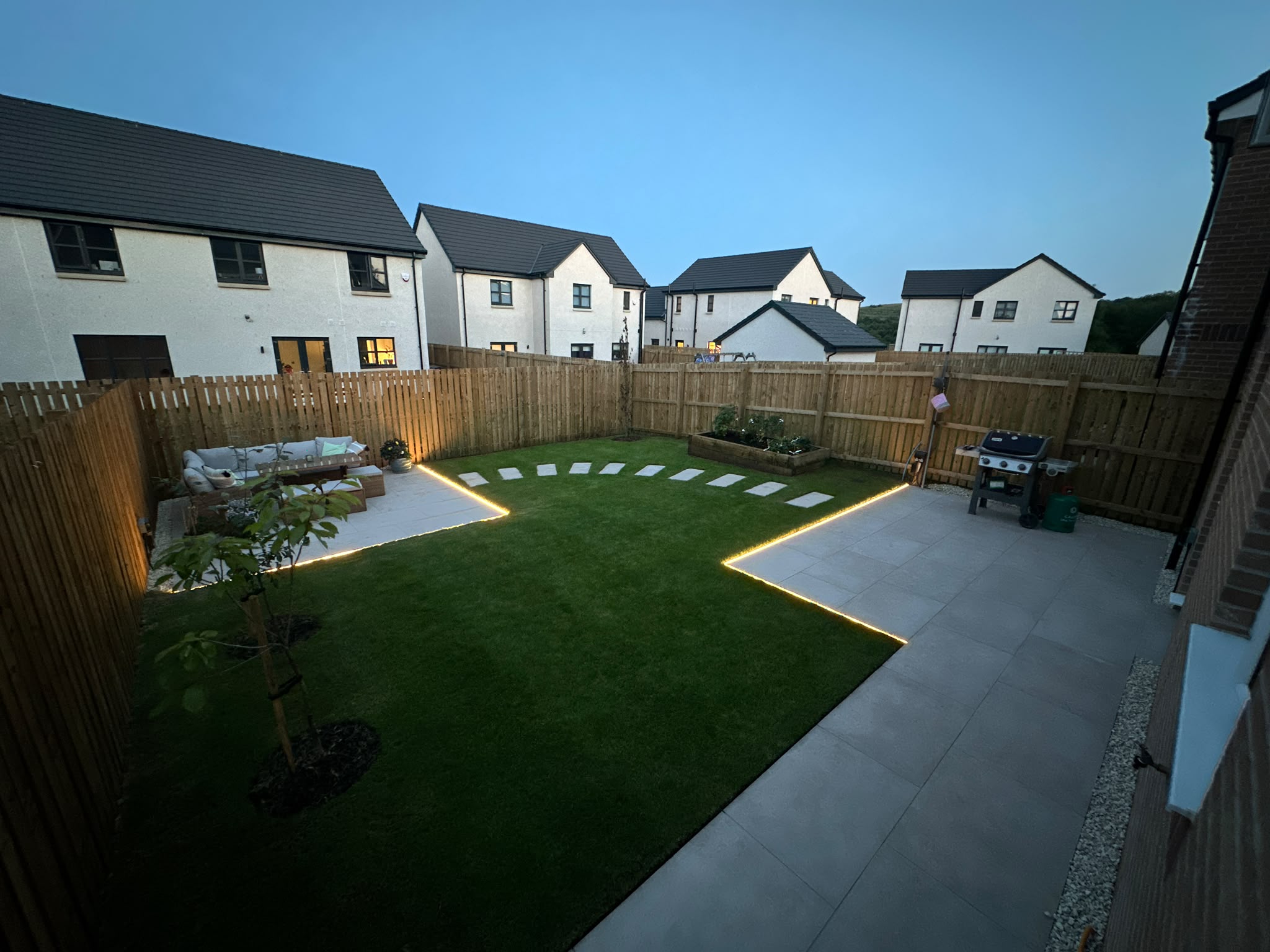Completed garden with paving, lawn, planting and lighting at dusk